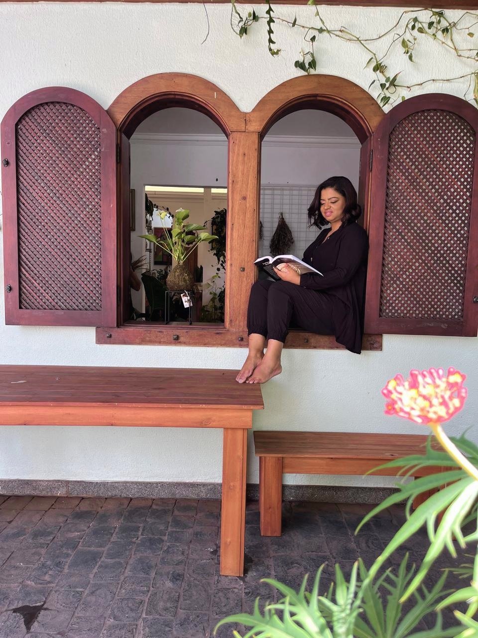 Raquel Cecília em momento de leitura, sentada em janela em arco